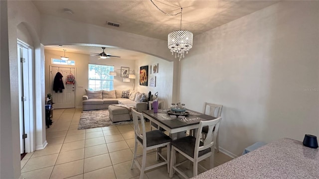 dining room featuring visible vents, arched walkways, baseboards, light tile patterned flooring, and ceiling fan with notable chandelier