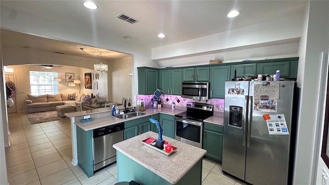 kitchen with stainless steel appliances, visible vents, a sink, green cabinetry, and a peninsula