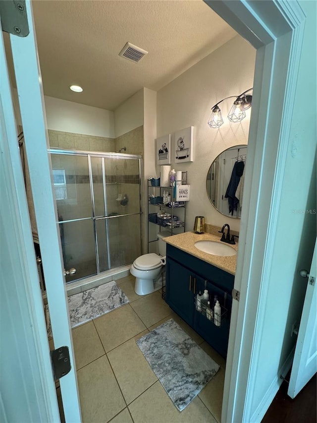 full bath with a textured ceiling, tile patterned flooring, vanity, visible vents, and a shower stall