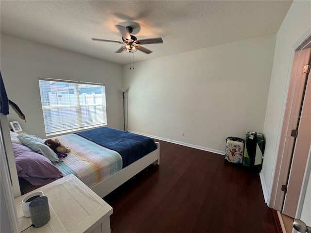 bedroom with dark wood-style floors, a textured ceiling, baseboards, and a ceiling fan