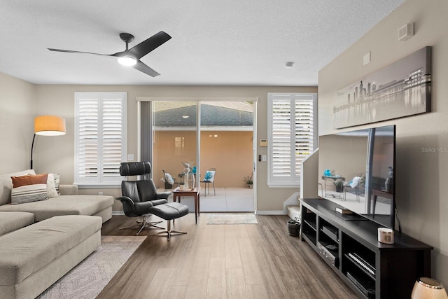 living room featuring hardwood / wood-style flooring, ceiling fan, and a textured ceiling