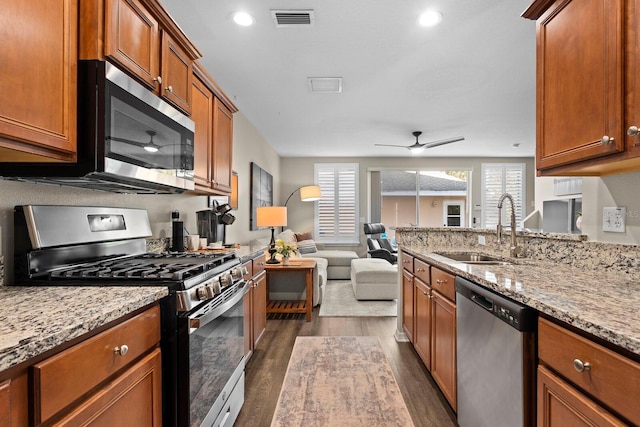 kitchen with light stone countertops, stainless steel appliances, dark hardwood / wood-style floors, and sink