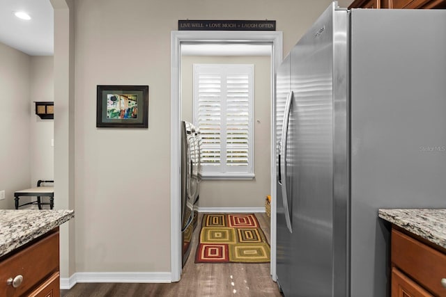 kitchen featuring light stone countertops, stainless steel fridge, and dark hardwood / wood-style floors