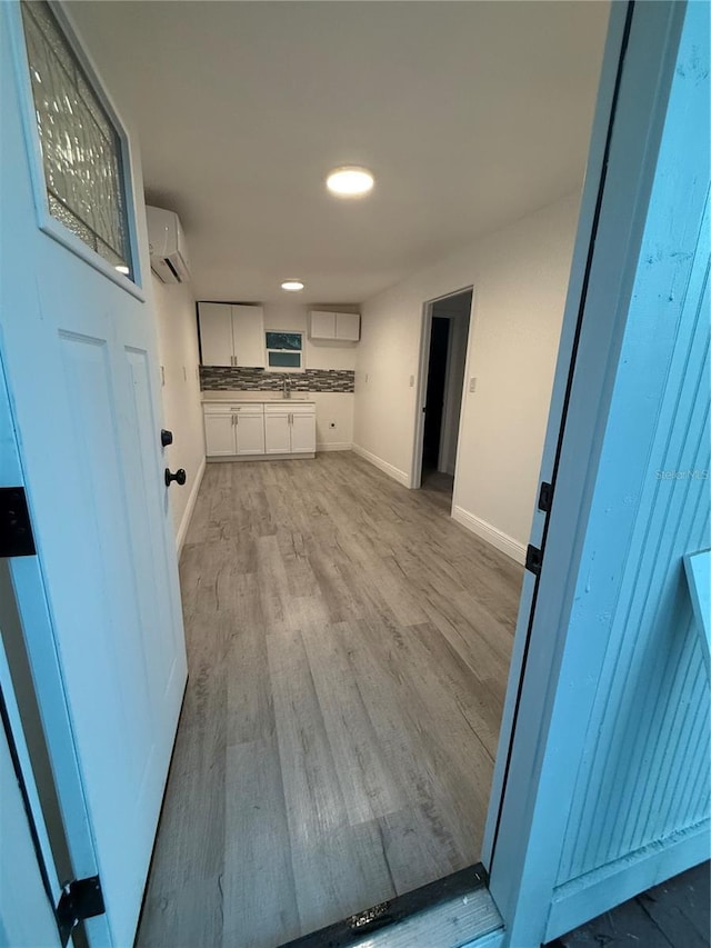 washroom with a wall unit AC and light hardwood / wood-style floors