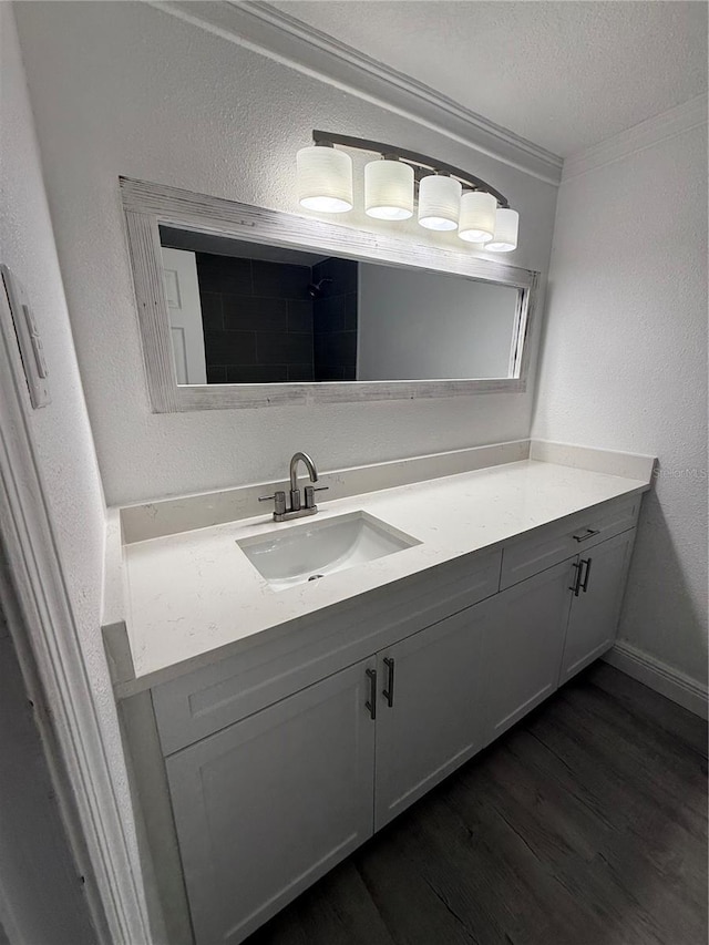 bathroom featuring vanity, hardwood / wood-style flooring, ornamental molding, and a textured ceiling