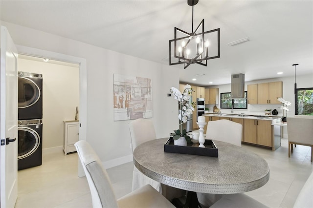 dining space featuring a chandelier and stacked washing maching and dryer