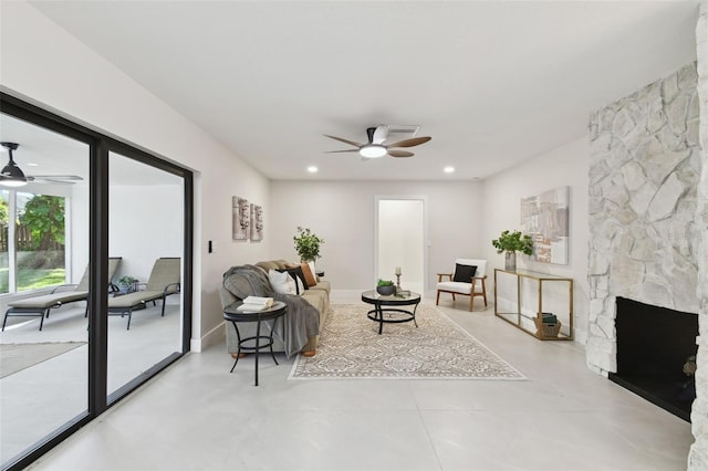 living room featuring a stone fireplace and ceiling fan