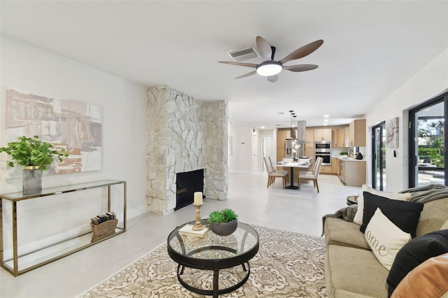 living room with ceiling fan and a stone fireplace