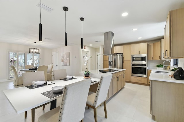 kitchen featuring appliances with stainless steel finishes, sink, light brown cabinets, a notable chandelier, and hanging light fixtures