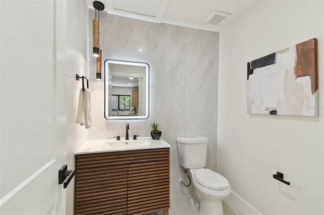 bathroom with vanity, toilet, and tile walls