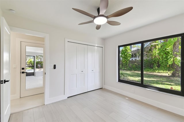 unfurnished bedroom featuring multiple windows, ceiling fan, a closet, and light hardwood / wood-style floors