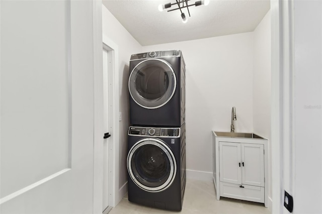 washroom featuring sink, stacked washing maching and dryer, and a textured ceiling