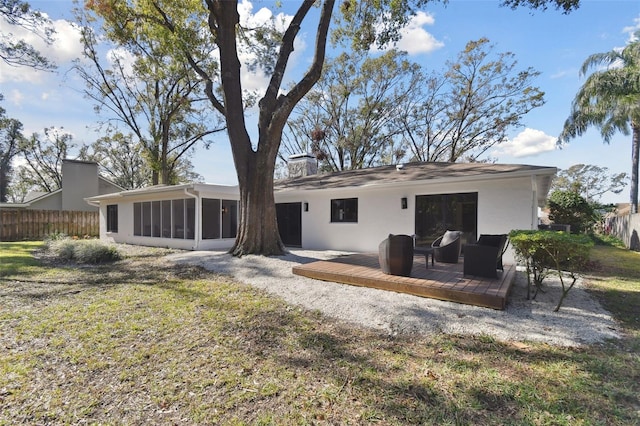 rear view of property featuring a yard, a wooden deck, and a sunroom