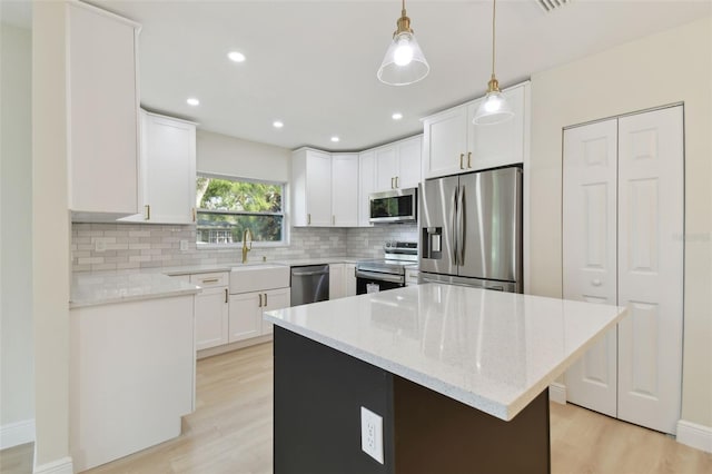 kitchen featuring white cabinetry, hanging light fixtures, a center island, and stainless steel appliances