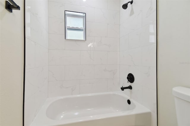 bathroom with toilet and tiled shower / bath