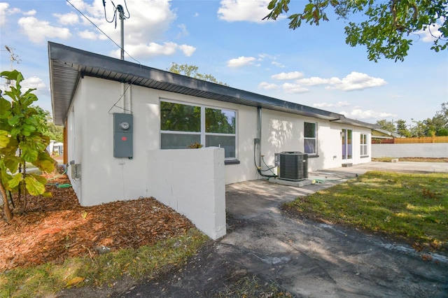 view of side of home with a patio area, a yard, and central AC