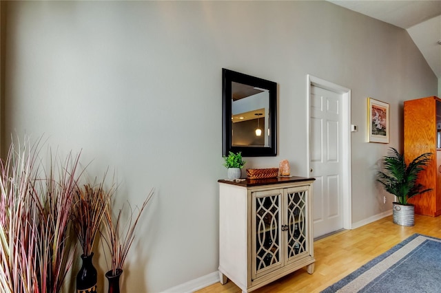 hallway featuring light wood-type flooring and vaulted ceiling