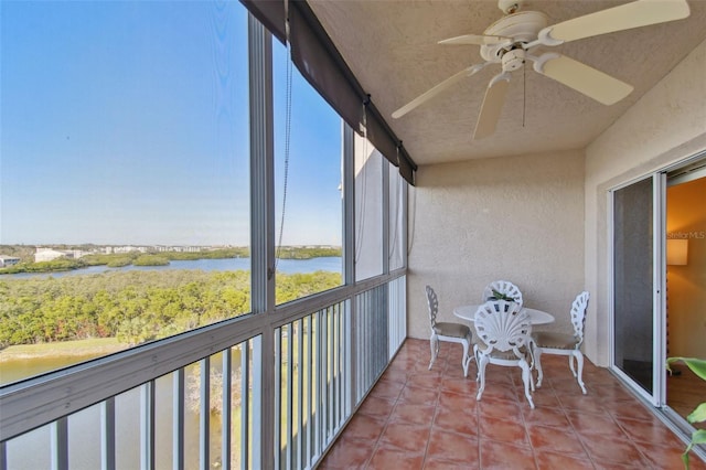 sunroom featuring ceiling fan, a wealth of natural light, and a water view