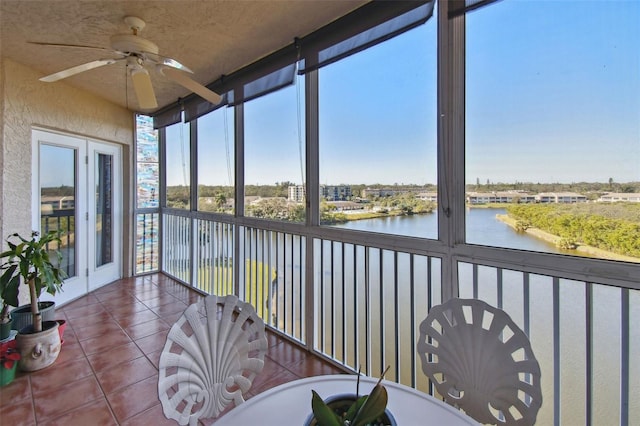 sunroom / solarium featuring ceiling fan and a water view