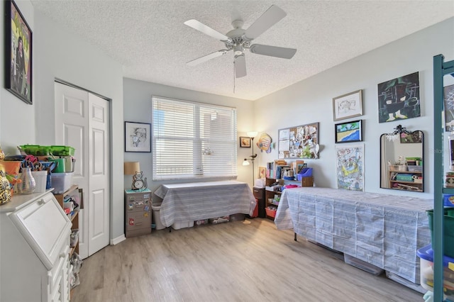 bedroom featuring ceiling fan, a closet, a textured ceiling, and light hardwood / wood-style flooring