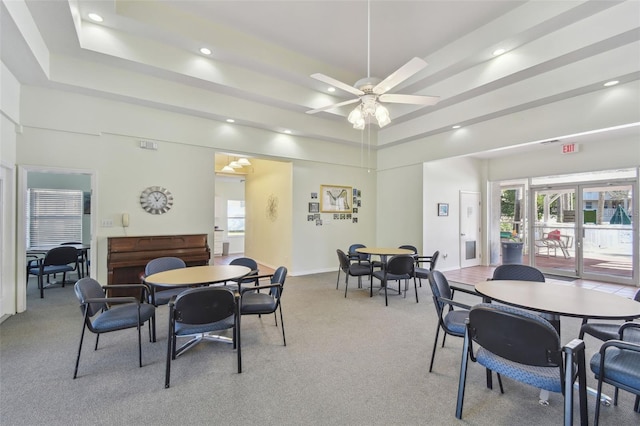 dining area with light carpet, ceiling fan, and a tray ceiling