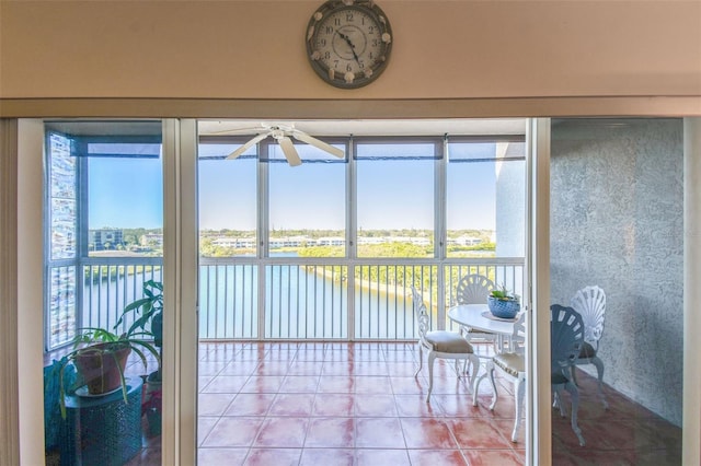 sunroom featuring a water view and ceiling fan