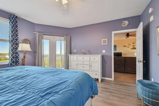 bedroom featuring a textured ceiling, ceiling fan, light hardwood / wood-style floors, and access to outside