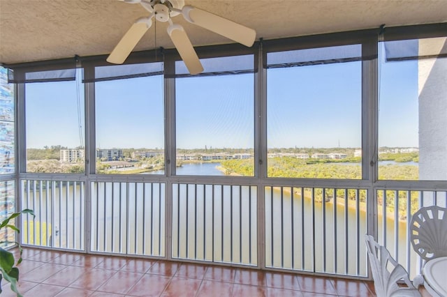 unfurnished sunroom featuring ceiling fan, a healthy amount of sunlight, and a water view