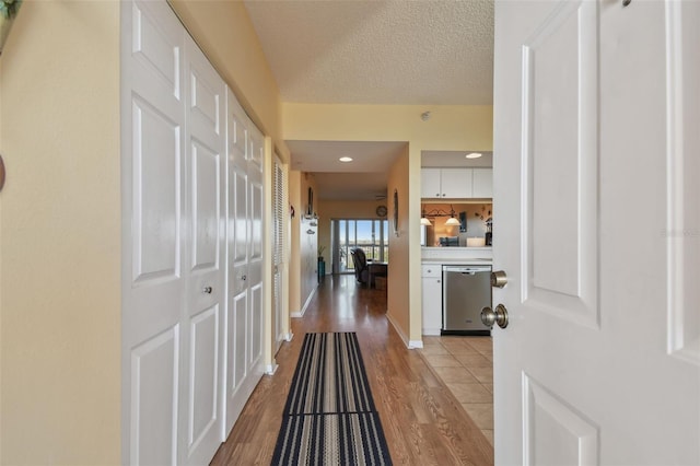 hall with light hardwood / wood-style floors and a textured ceiling