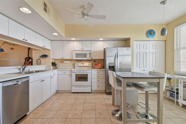 kitchen featuring white cabinets, hanging light fixtures, appliances with stainless steel finishes, and a textured ceiling