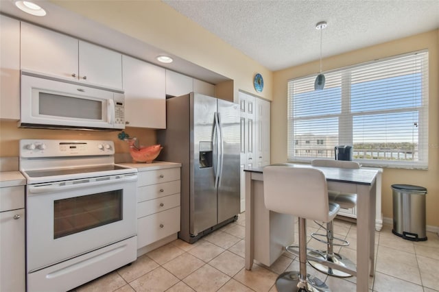 kitchen with pendant lighting, white appliances, white cabinetry, a textured ceiling, and light tile patterned floors