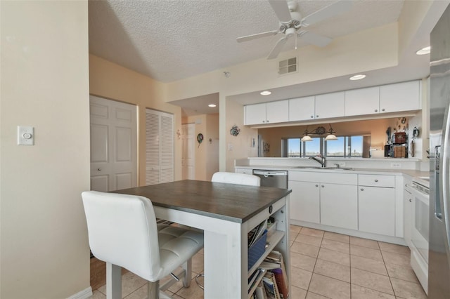 kitchen featuring light tile patterned flooring, sink, white cabinetry, and a textured ceiling