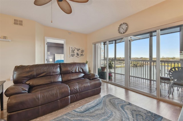 living room featuring ceiling fan, a water view, and light wood-type flooring