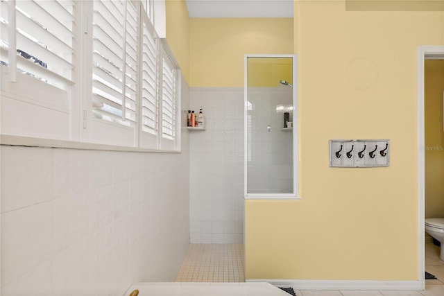 bathroom with tiled shower, tile patterned flooring, and toilet