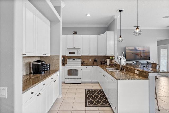 kitchen with kitchen peninsula, a breakfast bar, white cabinets, and white appliances