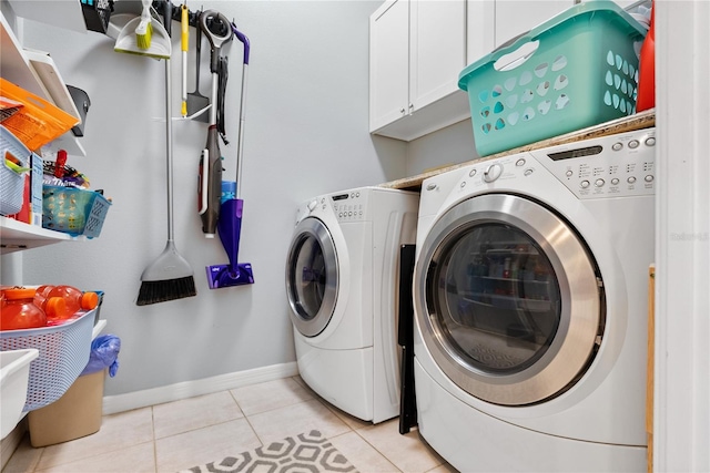 clothes washing area with washer and dryer, light tile patterned floors, and cabinets