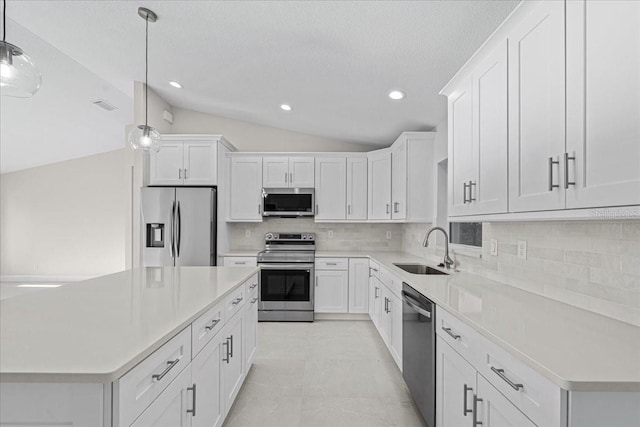 kitchen with stainless steel appliances, vaulted ceiling, sink, pendant lighting, and white cabinetry