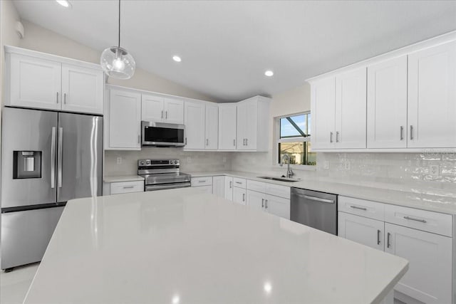 kitchen featuring sink, pendant lighting, vaulted ceiling, white cabinets, and appliances with stainless steel finishes