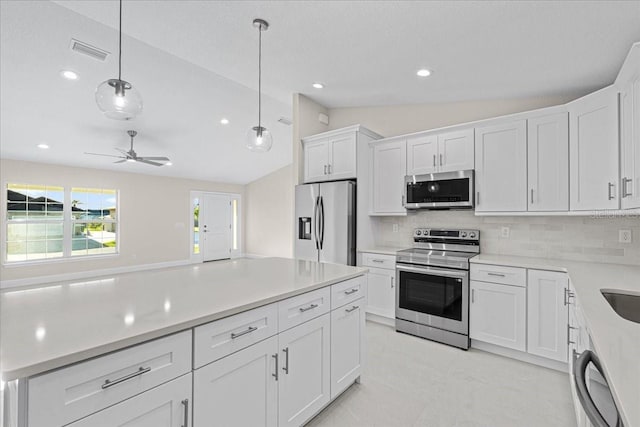 kitchen featuring decorative backsplash, white cabinetry, hanging light fixtures, and appliances with stainless steel finishes