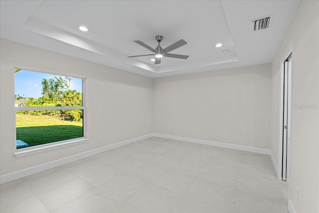 empty room featuring a tray ceiling and ceiling fan