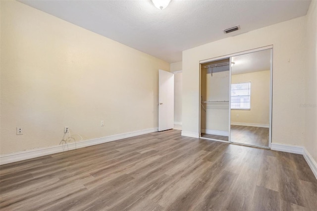 unfurnished bedroom with hardwood / wood-style floors, a textured ceiling, and a closet