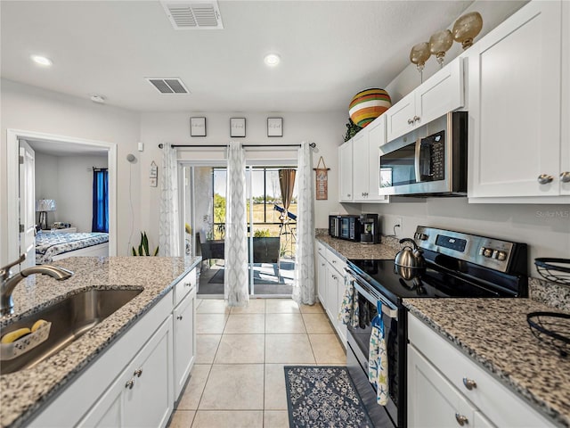 kitchen featuring white cabinetry, sink, light stone countertops, light tile patterned floors, and appliances with stainless steel finishes