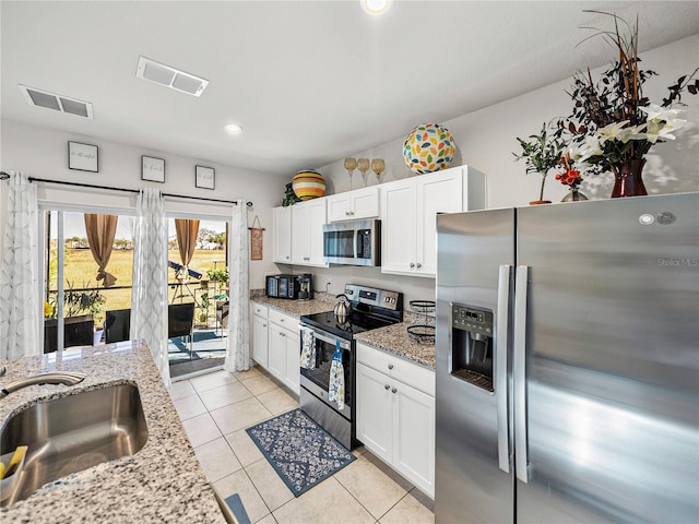 kitchen with white cabinets, sink, light tile patterned floors, and stainless steel appliances