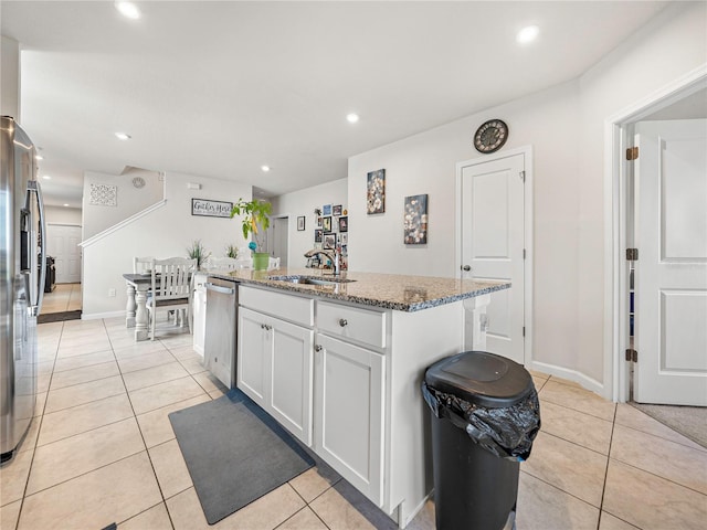 kitchen featuring a kitchen island with sink, dark stone counters, white cabinets, sink, and stainless steel appliances