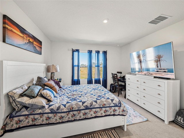 bedroom featuring light carpet and a textured ceiling