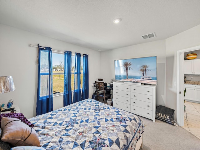 carpeted bedroom with a textured ceiling and ensuite bath