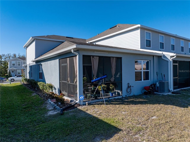 back of property featuring a sunroom, central AC unit, and a lawn