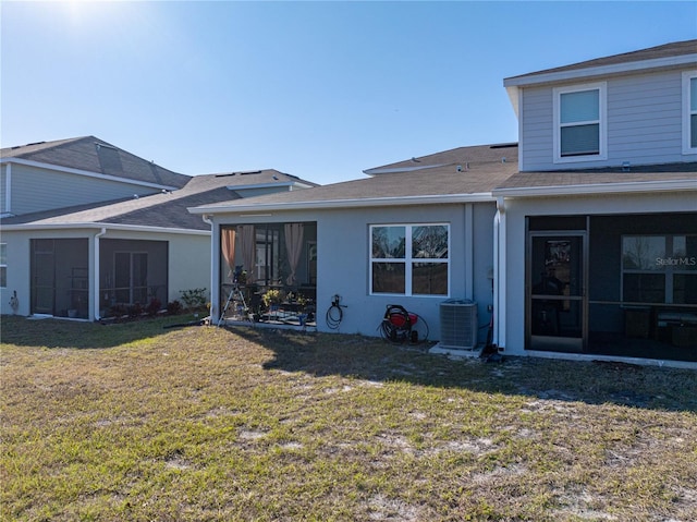 rear view of house with a sunroom, central air condition unit, and a lawn