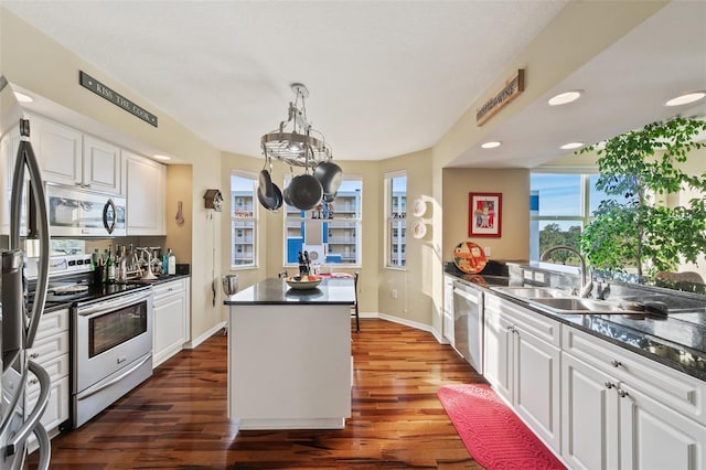 kitchen featuring dark wood-type flooring, white cabinets, sink, decorative light fixtures, and stainless steel appliances