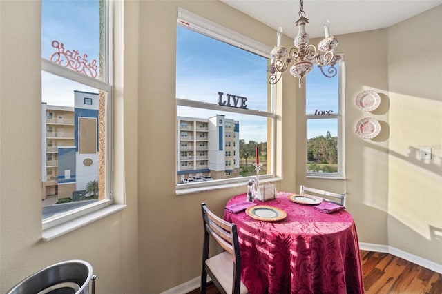 dining area featuring a healthy amount of sunlight, wood-type flooring, and a chandelier